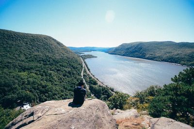 Rear view of man sitting on breakneck ridge against sky