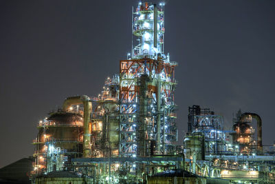 Low angle view of illuminated factory against sky at night