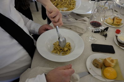 Hand of waiter serving pasta in bowl at restaurant