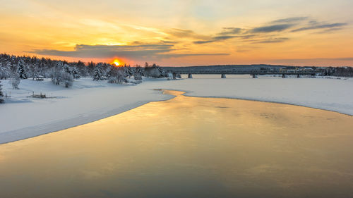 Scenic view of snow covered land against sky during sunset