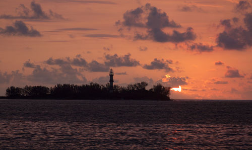 Scenic view of sea against cloudy sky during sunset