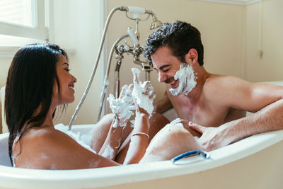 Woman applying shaving cream on boyfriend face