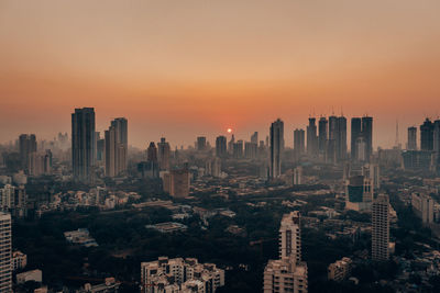 Aerial view of buildings in city against sky during sunset