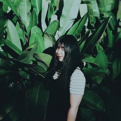 Young woman standing against plants