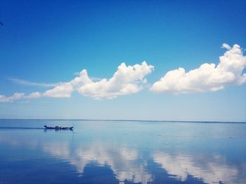 Boats in sea against cloudy sky