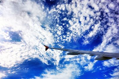 Low angle view of airplane wing against cloudy sky