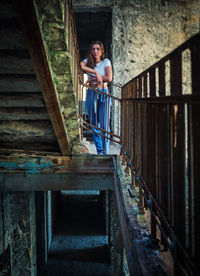 Sad pensive teenage girl standing on the stairs in an abandoned building