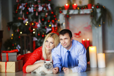 Portrait of couple lying on floor with cat during christmas