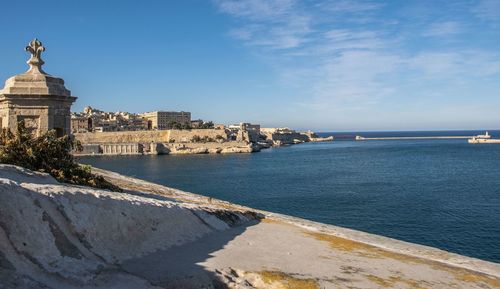 Buildings by sea against blue sky