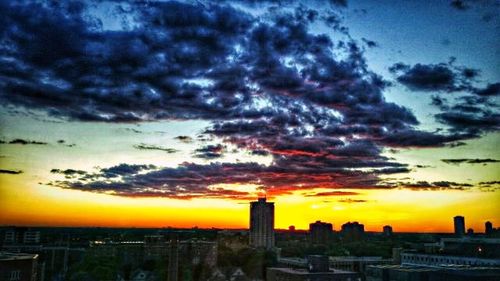 Silhouette of cityscape against cloudy sky at sunset