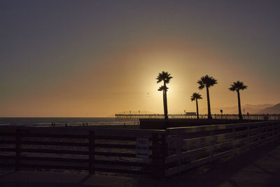 Silhouette palm trees on beach against clear sky at sunset