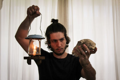 Side view of man holding illuminated light bulb