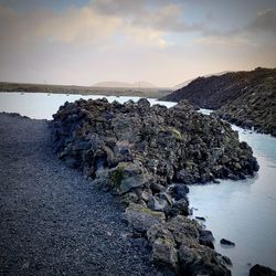 Rock formation on beach against sky during sunset