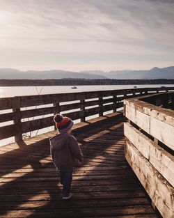 Rear view of woman walking on railing against sky