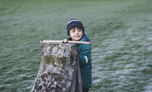 Smiling boy holding toy on built structure in park