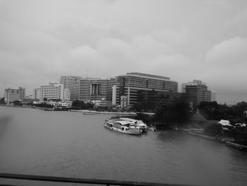 View of city at waterfront against cloudy sky