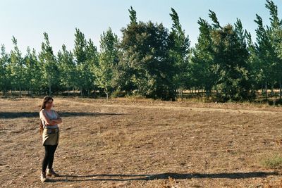 Woman standing on field against trees
