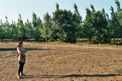 Woman standing on field against trees