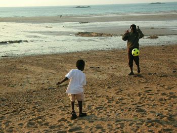Rear view of men standing at beach