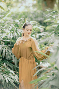 Portrait of young woman standing amidst plants