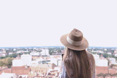 Rear view of woman looking at cityscape against sky