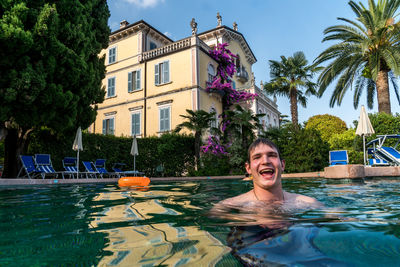 Portrait of smiling man in swimming pool against trees