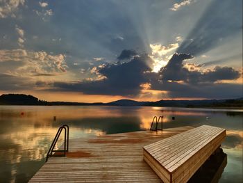 Pier over lake against sky during sunset