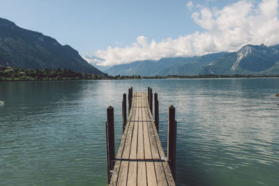 Pier over lake by mountains against sky