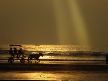 People riding horse on beach against sky