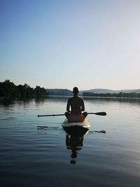 Man sitting in lake against clear sky