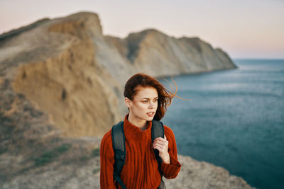 Young woman standing against sea