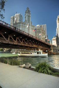 Bridge over river by buildings in city against sky