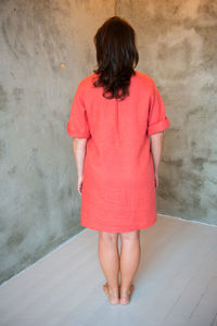 Woman in red dress standing against wall