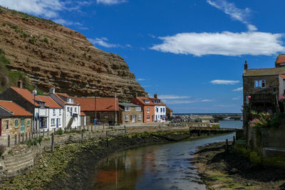 Buildings by river in town against sky