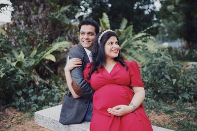 Portrait of smiling young couple against trees