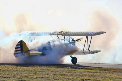 Airplane flying over field against sky