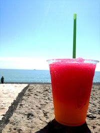 Close-up of drink on beach against clear sky