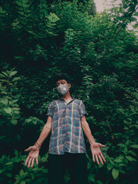 Portrait of young man standing against trees