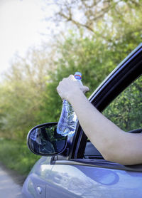 Hand holding water bottle in car window