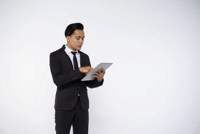 Young man looking away while standing against white background