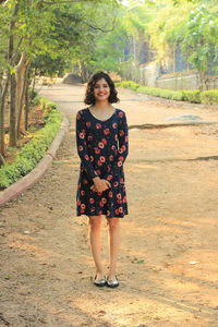 Portrait of smiling young woman standing against trees