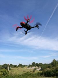 Low angle view of drone flying against blue sky