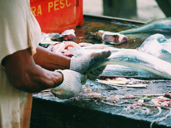 Midsection of man holding fish at market