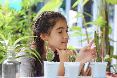 Girl with potted cacti on table