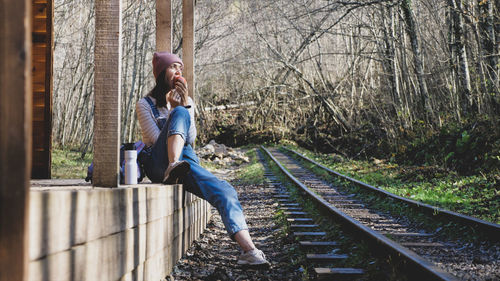 Full length of woman sitting on railroad track