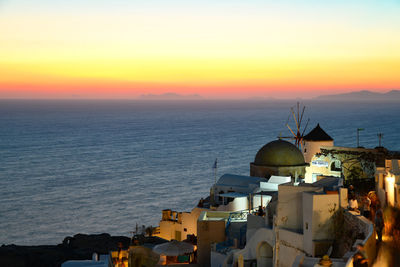 High angle view of buildings by sea against sky during sunset