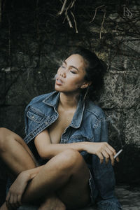 Young woman smoking while sitting outdoors