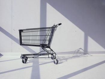 Close-up of shopping cart against gray wall