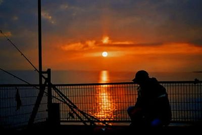 Silhouette of people in sea at sunset