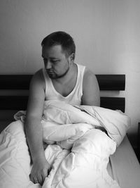 Young woman sitting on bed at home